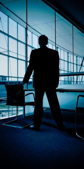 Business man looking out an office window.